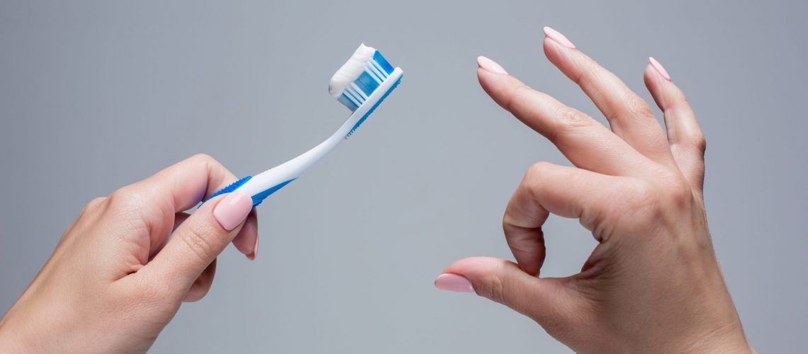 Toothbrush in woman's hands on gray background